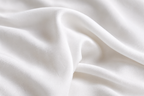 Close-up of draped white fabric with soft folds and a smooth texture.