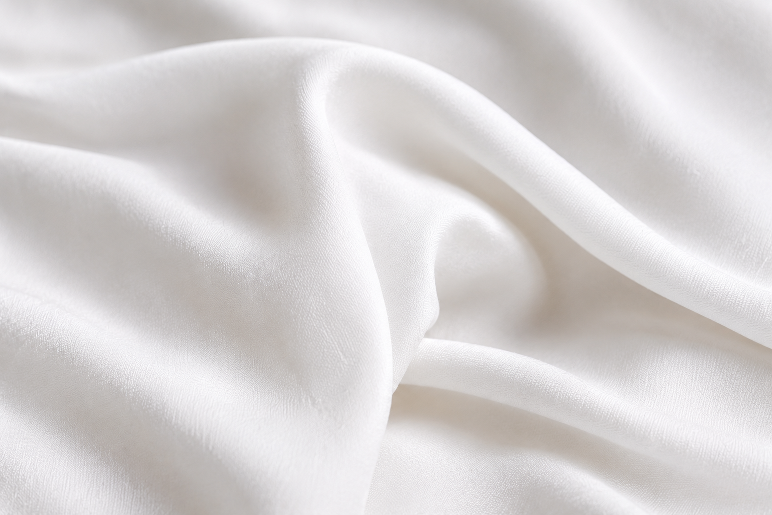 Close-up of draped white fabric with soft folds and a smooth texture.