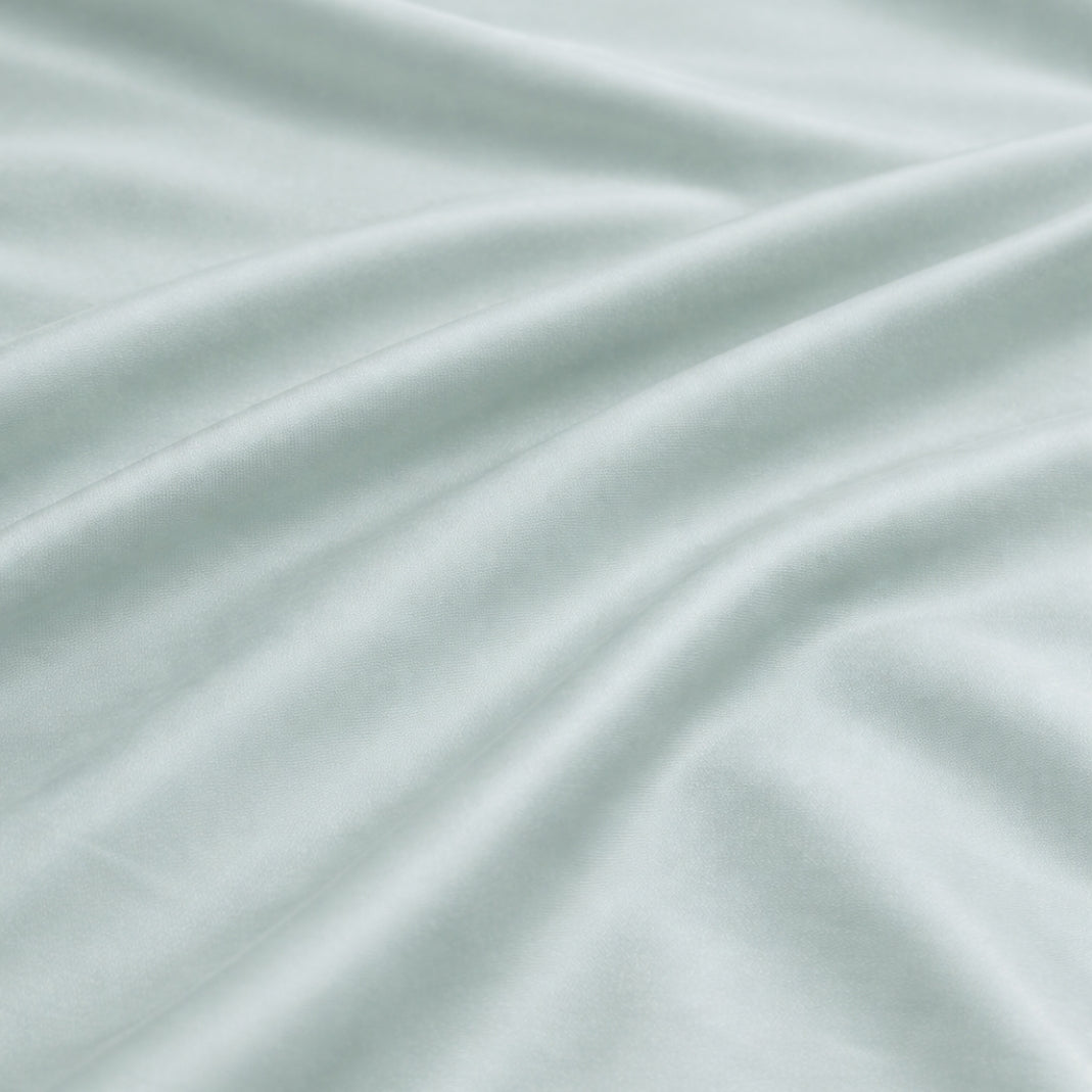 Close-up of sage bamboo duvet cover fabric showing a silky sateen weave and shiny finish.
